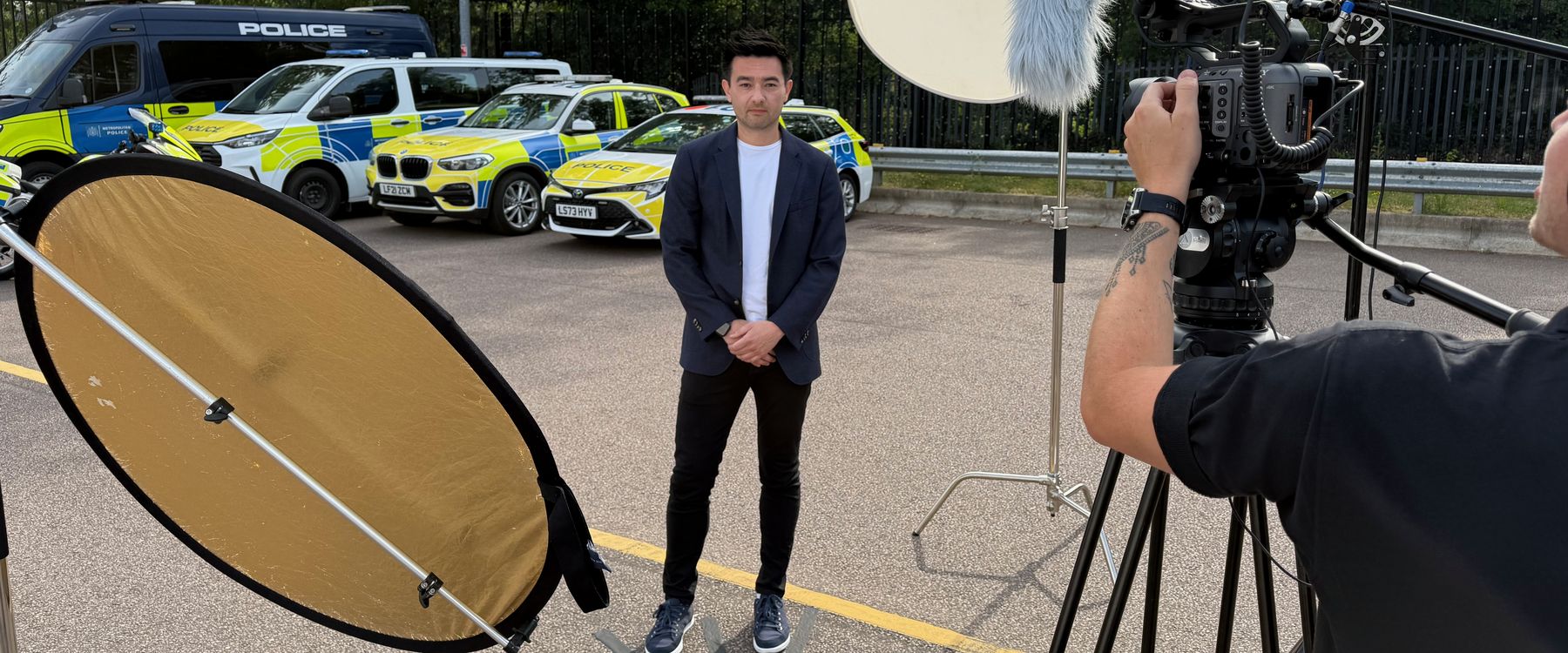 Thomas Li being filmed in front of a Metropolitan Police vehicle lineup